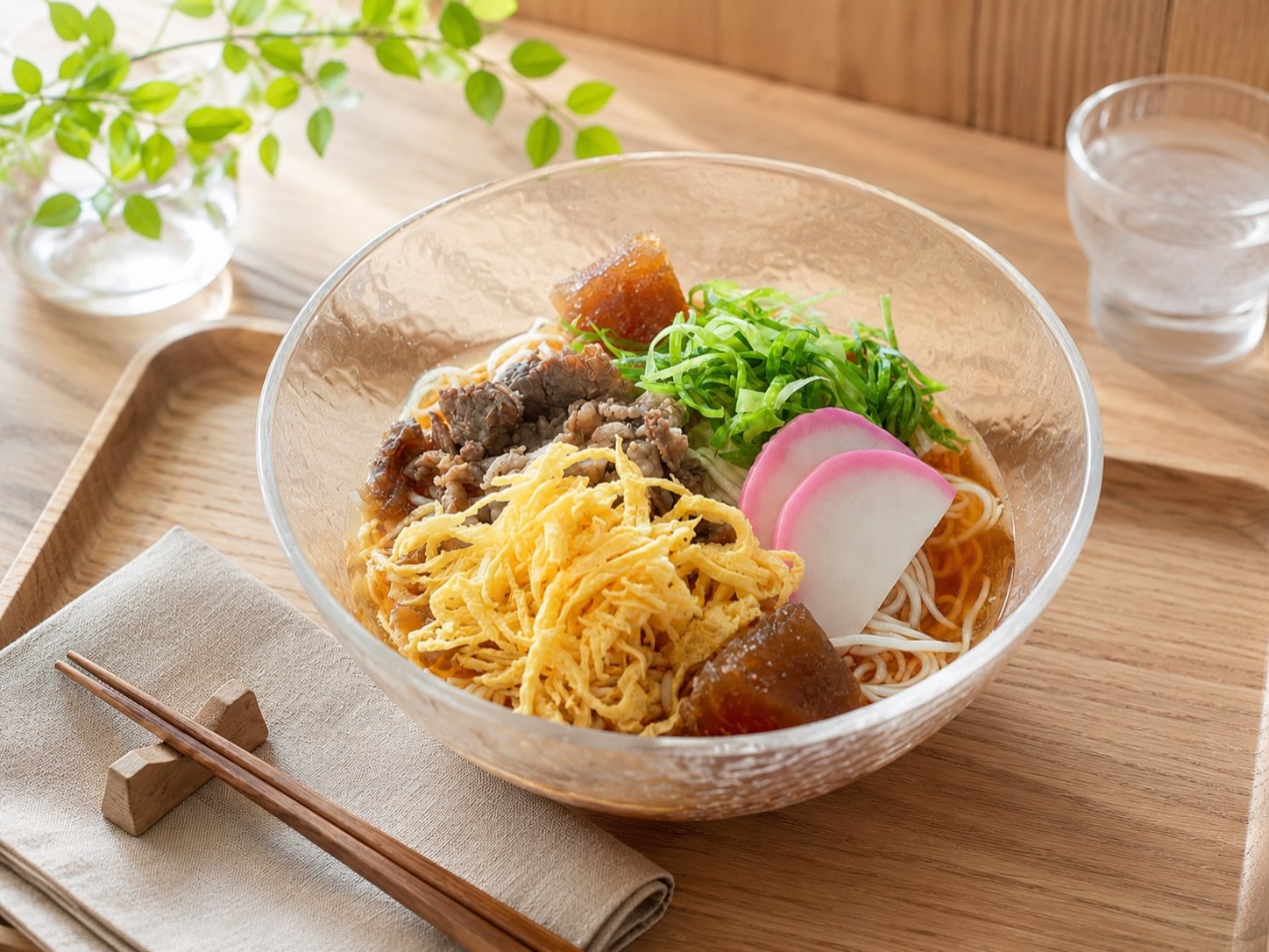 ガラスの器に盛られた冷やしそうめん。煮込んだ牛肉・錦糸卵・かまぼこ・ねぎと出汁氷入り